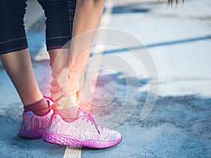 Young woman suffering from an ankle injury while exercising and running.