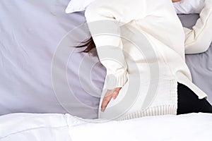 Young woman suffering back pain from uncomfortable bed. Healthcare medical or daily life concept