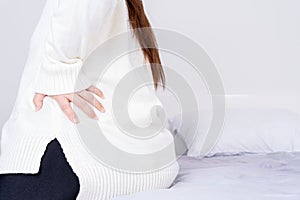 Young woman suffering back pain from uncomfortable bed. Healthcare medical or daily life concept