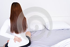 Young woman suffering back pain from uncomfortable bed. Healthcare medical or daily life concept