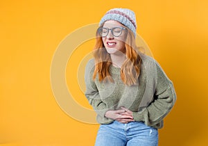 Young woman suffering from bellyache - stomachache, isolated on yellow background. Beautiful female person with chronic gastritis