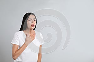 Young woman suffering from breathing problem on light background. Space for text