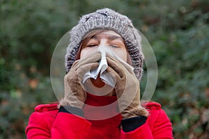 Young woman suffering from a cold or flu blowing her nose