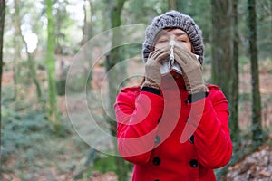 Young woman suffering from a cold or flu blowing her nose