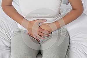 Young woman suffering from cystitis on bed, closeup