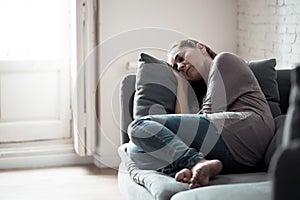 Young woman suffering from depression feeling sad and lonely on sofa at home