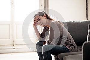 Young woman suffering from depression feeling sad and lonely on sofa at home