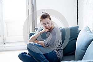 Young woman suffering from depression feeling sad and lonely on sofa at home