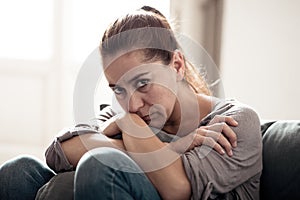 Young woman suffering from depression feeling sad and lonely on sofa at home