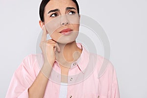 Young woman suffering from ear pain on light grey background