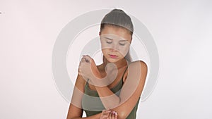 Young woman suffering from elbow injury, looking to the camera