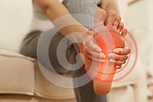 Young woman suffering from foot pain indoors, closeup
