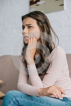 young woman suffering from jaw pain and looking away