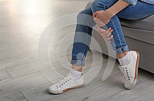 Young woman suffering from leg pain indoors, closeup