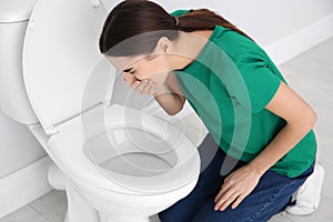 Young woman suffering from nausea over toilet bowl