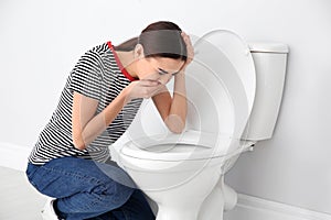 Young woman suffering from nausea over toilet bowl