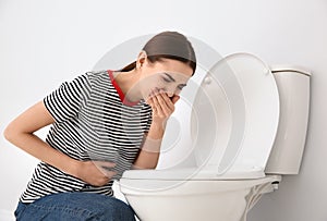 Young woman suffering from nausea at toilet bowl