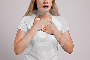 Young woman suffering from pain during breathing on light grey background, closeup