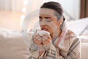 Young woman suffering from runny nose in living room
