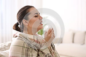 Young woman suffering from runny nose in living room