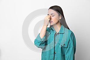 Young woman suffering from runny nose on white background. Space for text