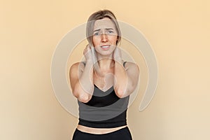 Young woman suffering from severe depression, anxiety, sadness, crying, standing over beige background. Unhappy girl feeling