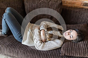 High angle view of young woman suffering from stomachache on sofa at home