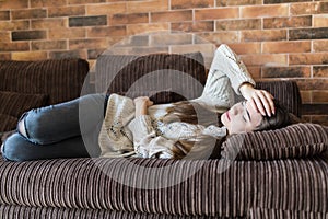 High angle view of young woman suffering from stomachache on sofa at home