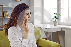 Young woman suffering from strong teeth pain or feeling discomfort after tooth extraction
