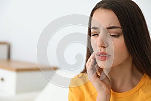 Young woman suffering from strong tooth pain at home