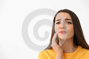 Young woman suffering from strong tooth pain on light background