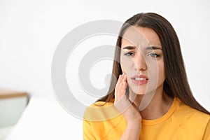 Young woman suffering from strong tooth pain, space for text