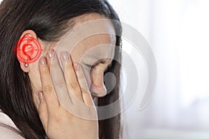 Young woman suffering of tinnitus disease, insomnia or stress concept, sick female having an ear pain touching her