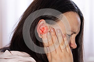 Young woman suffering of tinnitus disease, insomnia or stress concept, sick female having ear pain touching her painful