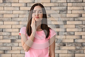 Young woman suffering from toothache on blurred background