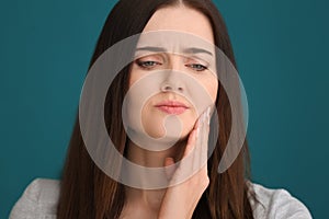 Young woman suffering from toothache on color background