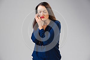 Young woman suffers from pain, feels sick, ill and weakness isolted on studio background