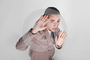 Young woman in suit evading something on light grey background, above view