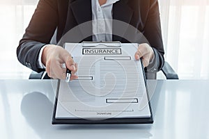 Young woman in suit in his office showing an insurance policy an