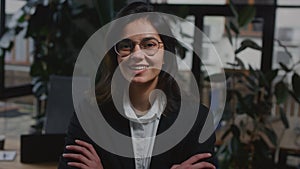 young woman in a suit stands in the office, smiling. The CEO girl is doing a successful business