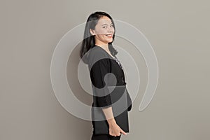 Young woman in a suit stands sideways while holding a folder