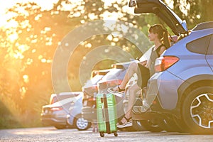 Young woman with suitcase bag waiting near her car. Travelling and vacations concept