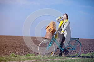 Young woman with suitcase and bike at outdoor countryside.