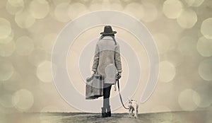 Young woman with suitcase and dog standing on the road