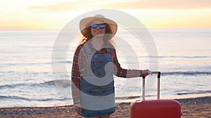 Young woman with a suitcase on the sunny beach