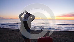 Young woman with a suitcase on the sunny beach