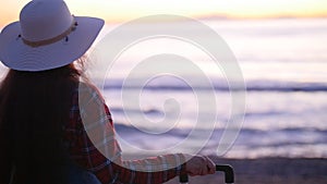 Young woman with a suitcase on the sunny beach