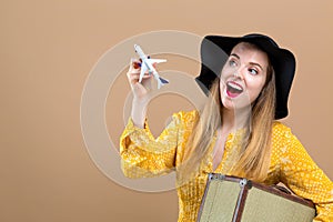 Young woman with a suitcase and toy airplane travel theme