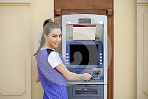 Young woman in summer dress using an automated teller machine