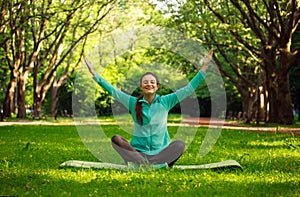 Young woman in summer park doing yoga with closed eyes